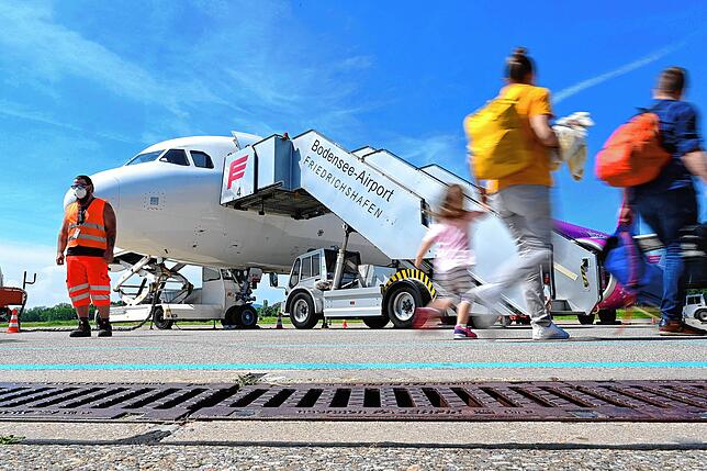 Passagiere laufen auf dem Bodensee-Airport mit Gepäck zum Flieger nach Skopje in Nordmazedonien.