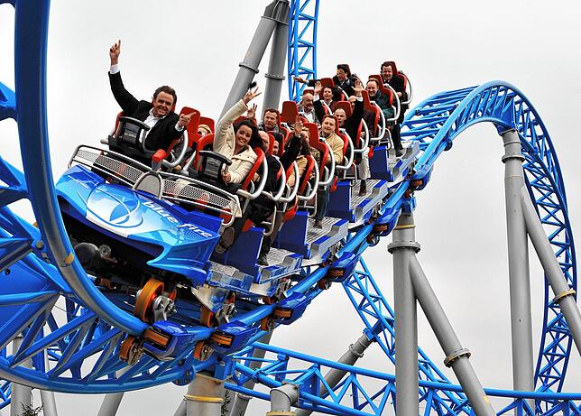 Eine Wagenkette der Achterbahn Blue Fire Megacoaster rast über die Strecke.