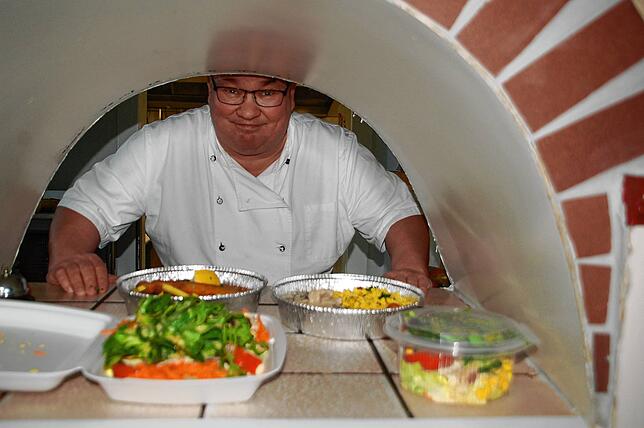 Olaf Hesse vom Kaiser richtet das Essen in Alu- und Plastikschalen.