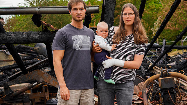 Jonas Oßwald und seine Schwester Aline Widmann, die ihren zehn Monate alten Sohn Gabriel auf dem Arm hat, vor den Trümmern der Scheune ...