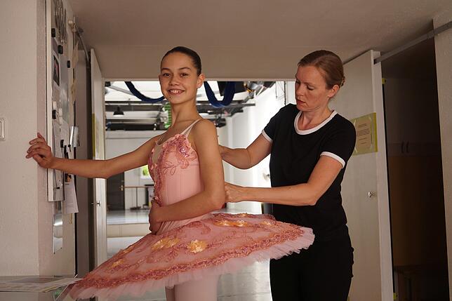 Tanzpädagogin Judith Geibel hilft Zora beim Anziehen des Tutu.