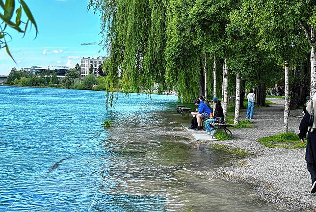 Das Wasser läuft den Leuten auf der Bank im Herosé-Park schon fast über die Füße, trotzdem beobachten sie gespannt die Überschwemmungen.