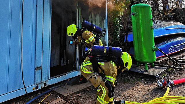 Feuerwehrleute vor dem qualmenden Baucontainer am Fährgelände der Stadtwerke.