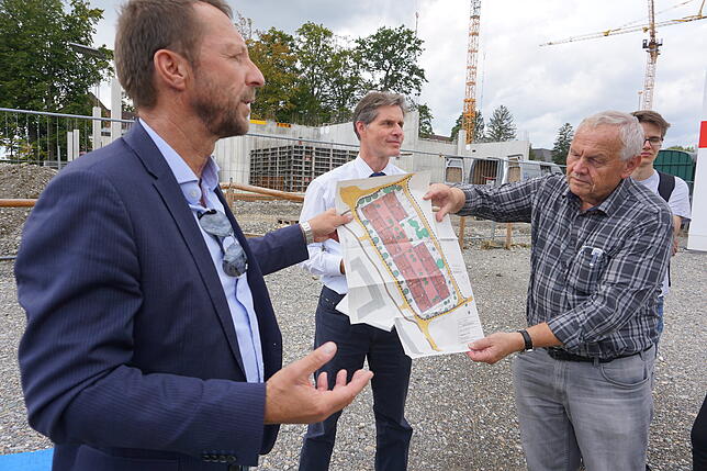 Baubürgermeister Stefan Köhler (links) erläutert den Stadträten bei der Baustellentour auf dem Plan die Neubauten, die die SWG im ...
