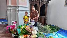 Ursel Weigert in der Benediktinerkirche inmitten der vielen Blüten mit ihrem kleinen Helfer Felix.