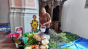 Ursel Weigert in der Benediktinerkirche inmitten der vielen Blüten mit ihrem kleinen Helfer Felix.