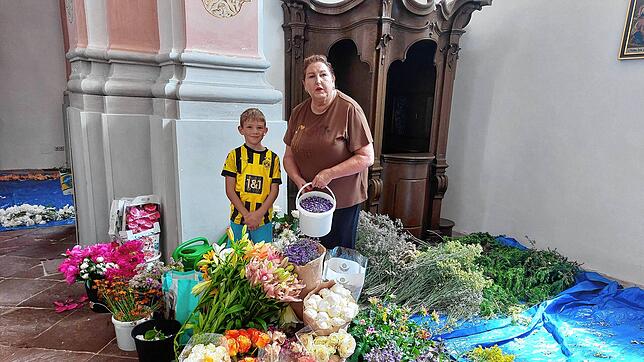 Ursel Weigert in der Benediktinerkirche inmitten der vielen Blüten mit ihrem kleinen Helfer Felix.