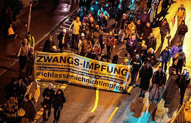 Demonstranten mit einem Transparent, das vor einer Zwangsimpfung warnt, protestieren in Stuttgart gegen die Corona-Maßnahmen. Viele ...