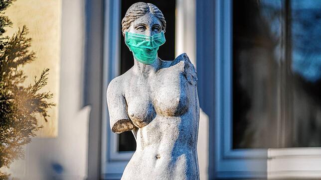 Eine Replik einer berühmten antiken Statue, der Venus von Milo, steht mit einem Mundschutz in einem Frankfurter Vorgarten.