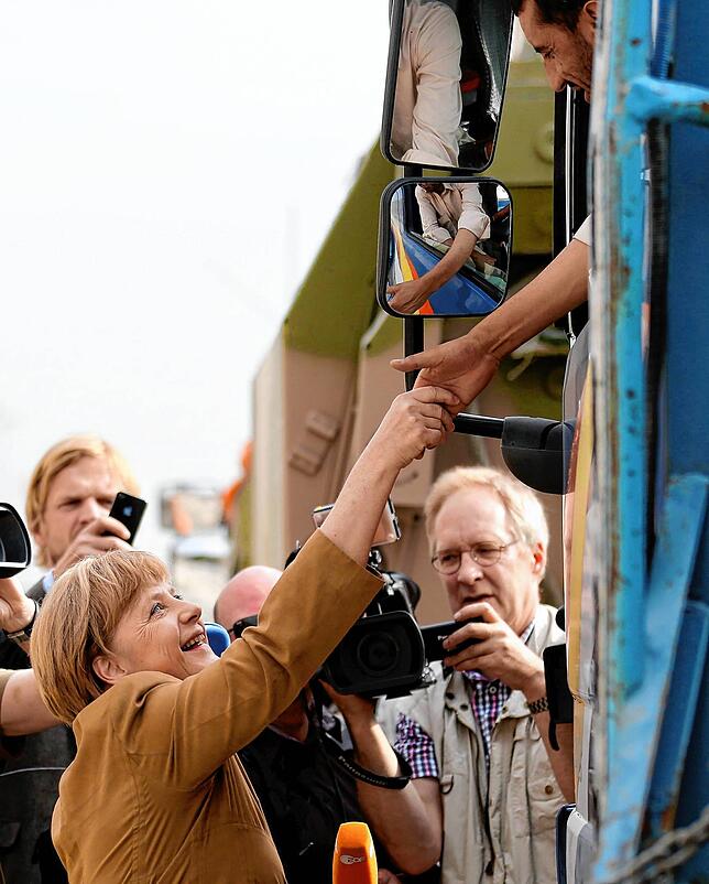 Bundeskanzlerin Angela Merkel (l, CDU) besucht 2013 im Feldlager in Kundus Soldaten der Bundeswehr und gibt dabei einem lokalen Fahrer ...