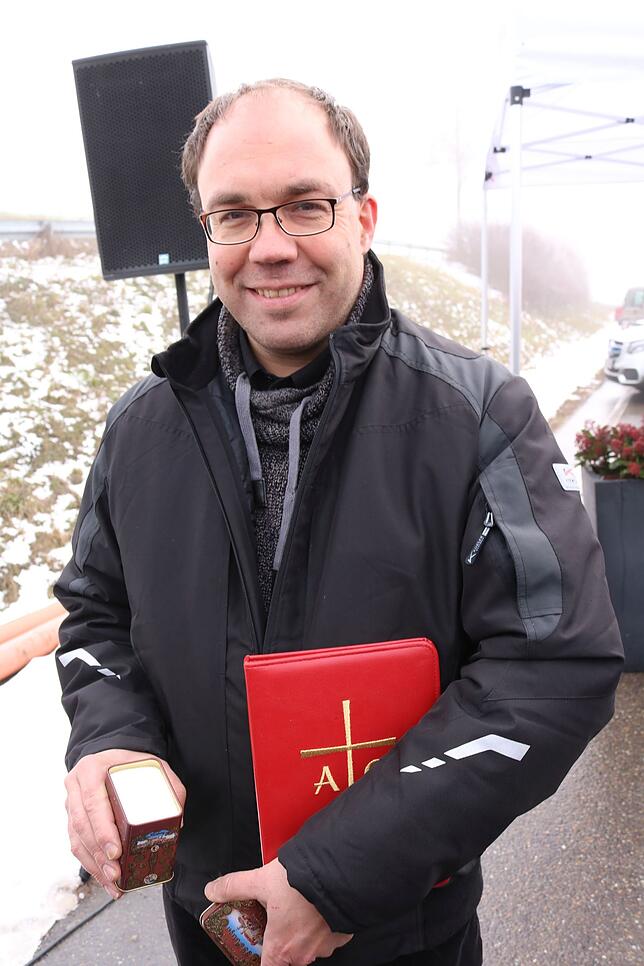 Gemeindereferent Harald Frey spricht bei der Einweihung einen Segen und streut Salz auf die Fahrbahn.