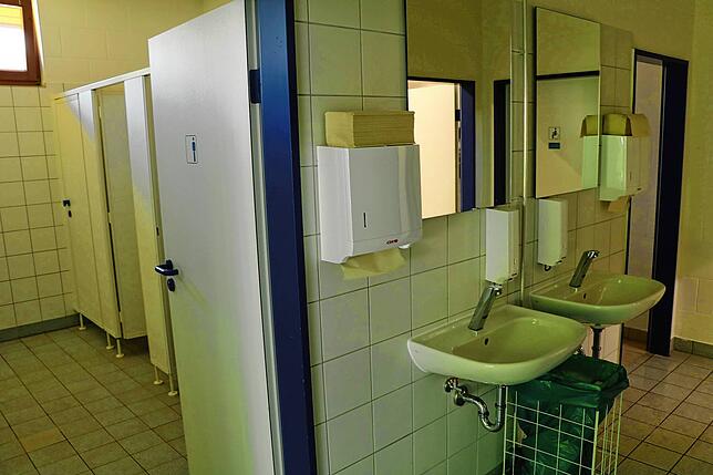 Sauber und in hellem Weiß gefliest stellen sich die Handwaschbecken in der Herrentoilette dar.