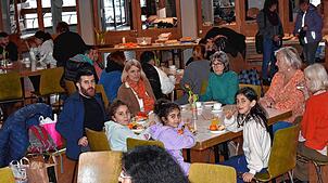 Helfer und Geflüchtete tragen zur gelungenen Veranstaltung bei, indem sie köstliche Kuchen und Gebäck mitbringen und miteinander genießen.