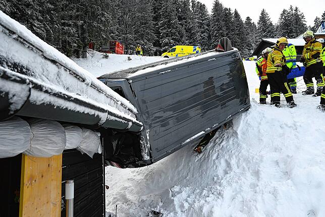 Das rutschende Auto wird von Hausdach und Schneemassen aufgehalten.