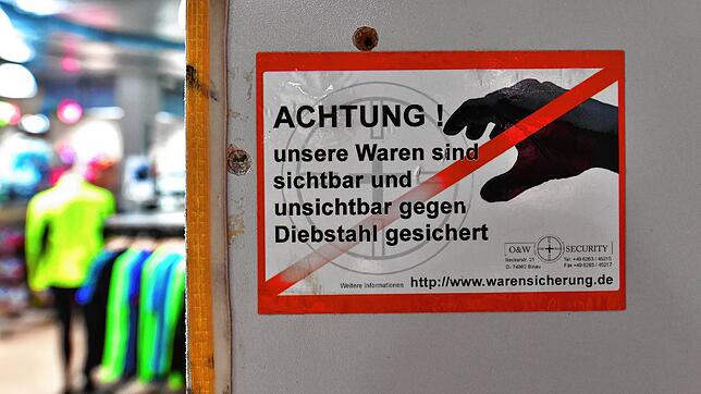 Ein Aufkleber warnt mögliche Täter vor Ladendiebstahl.