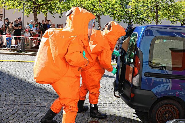 Einsatzkräfte im Vollschutzanzug bergen das Gefahrengut aus dem Unfallfahrzeug.