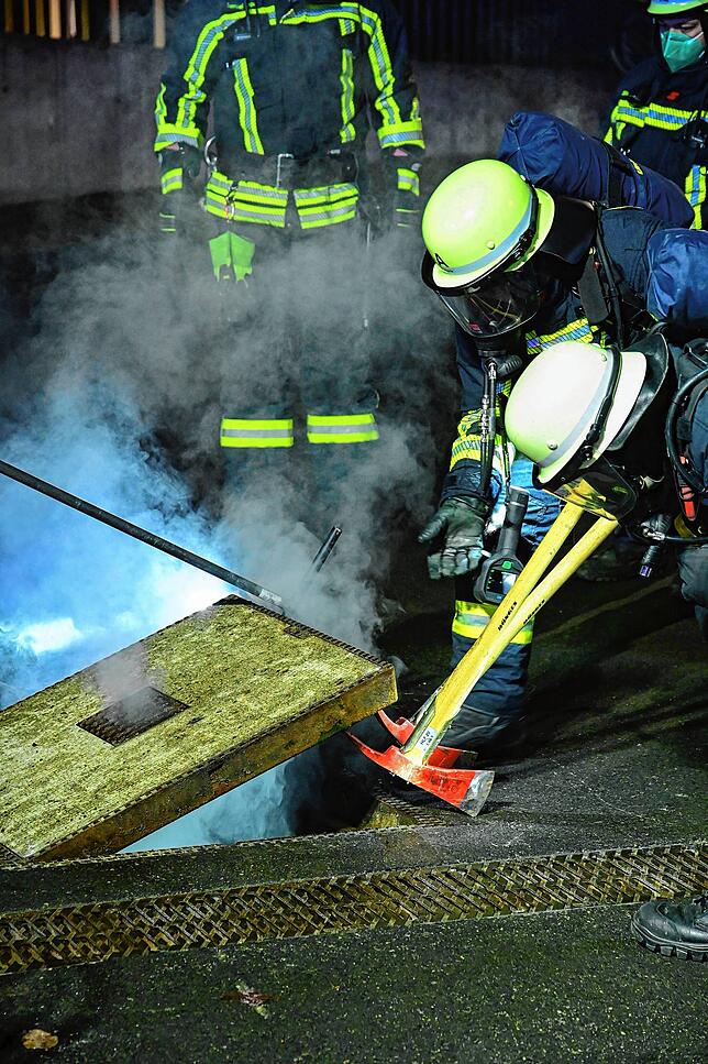 Die Feuerwehr öffnet den Schacht, aus dem eine Rauchentwicklung festzustellen ist.