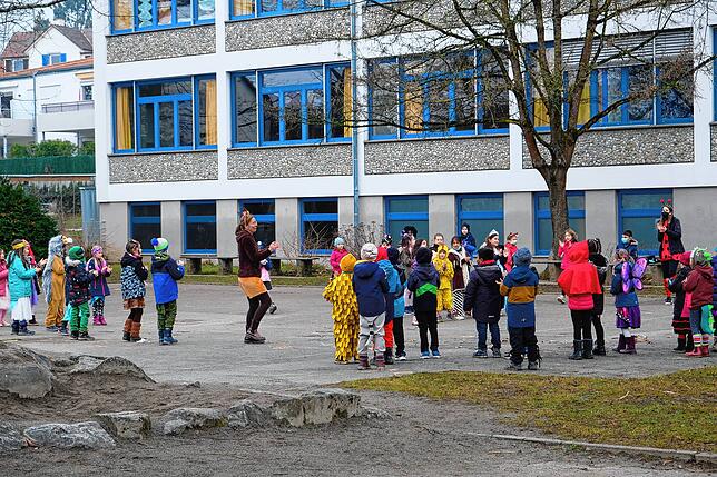 Die ersten und zweiten Klassen tanzen auf dem Schulhof.