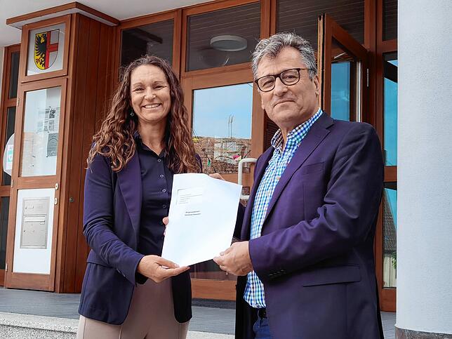 Jacqueline Alberti übergibt ihre Unterlagen Hasan Ögütcü, dem stellvertretenden Vorsitzenden des Gemeindewahlausschusses.