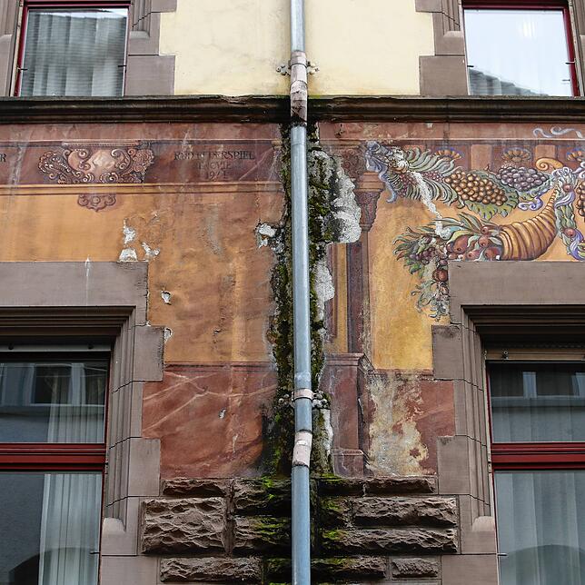 Das Dach und die Fallrohre sind undicht. Die Nässe ist der Grund, warum der Putz bröckelt.