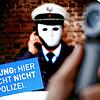 Ein Telefonhörer ist vor einem Plakat der Polizei mit der Aufschrift &bdquo;Achtung: Hier spricht NICHT die Polizei&ldquo; zu sehen. ...
