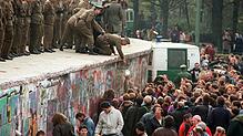 11. November 1989: DDR-Grenzposten stehen auf der Mauer vor dem Brandenburger Tor und sprechen zu DDR-Bürgern, die durch die Stadt strömen.