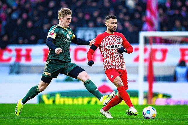 Union Berlins Mikkel Kaufmann (l) in Aktion gegen Freiburgs Manuel Gulde (r).