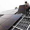 Handwerker montieren auf dem Dach eines Wohnhauses Solarmodule. Die können nicht nur gekauft, sondern auch gemietet werden.