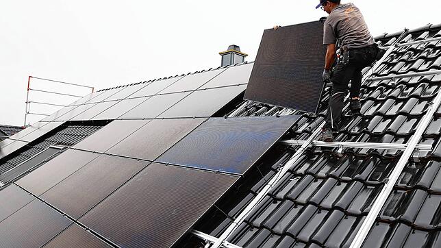 Handwerker montieren auf dem Dach eines Wohnhauses Solarmodule. Die können nicht nur gekauft, sondern auch gemietet werden.