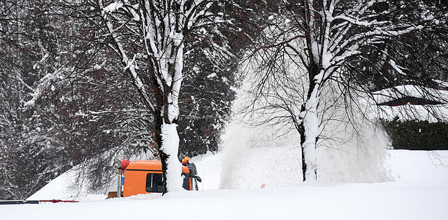 Ein Räumfahrzeug mit Schneefräse im bayerischen Siegsdorf befreit eine Straße von den Schneemassen.