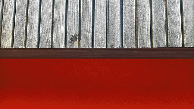 Die Fassade des Gebäudes besteht aus lasiertem Weißtannenholz und einer feuerwehrrot gestrichenen Massivwand.