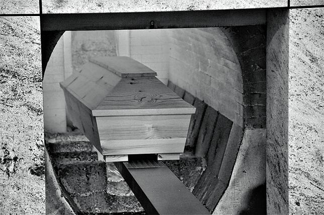 Ein Holzsarg fährt in die Brennkammer ein. Bei etwa 980 Grad verbrennen Körper und Gehäuse in etwa einer Stunde.