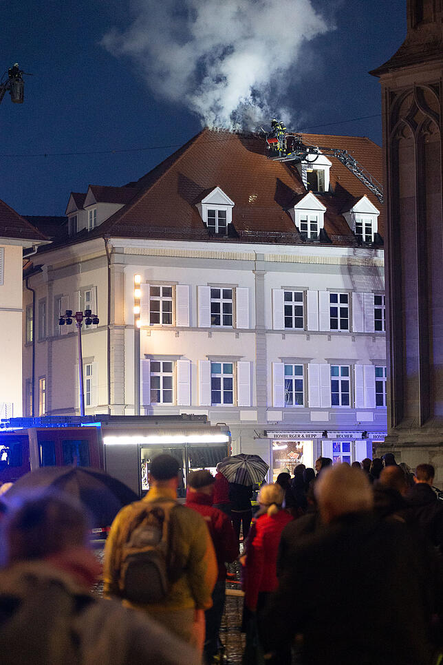 Ein Dachstuhl am Münsterplatz in Konstanz brennt. Viele Passanten bleiben stehen, um den Löscharbeiten der Konstanzer Feuerwehr zuzusehen.