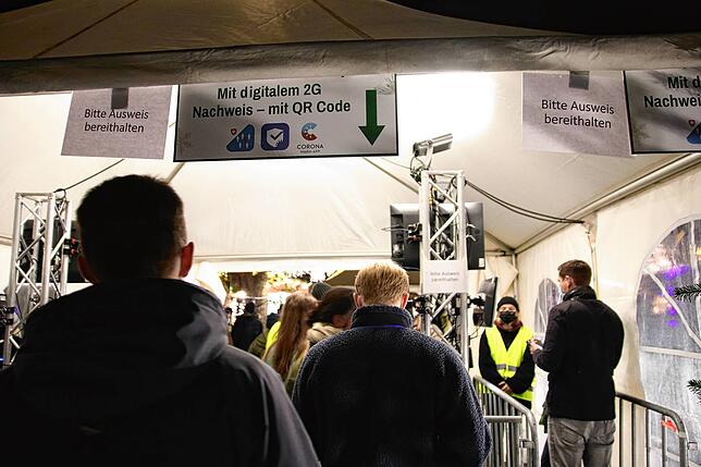 Eine Besucherin lässt ihren digitalen Impfnachweis am Eingang zum Markt einscannen.