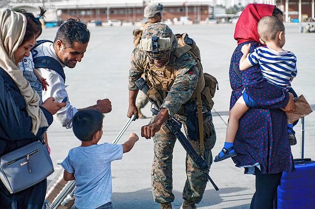 Ein US-Marine zusammen mit einer afghanischen Familie am Flughafen in Kabul.