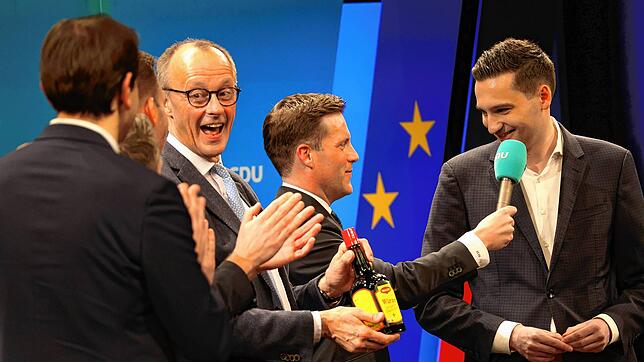 CDU-Kanzlerkandidat Friedrich Merz freut sich beim Wahlkampfbesuch in Singen über eine Maggi-Flasche als Andenken. Mit ihm auf der Bühne ...
