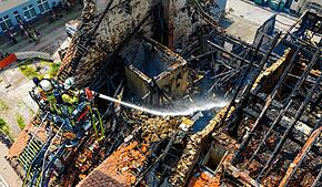 Zwei Feuerwehrleute spritzen am Sonntagmittag Wasser in die Brandruine zwischen Gerberstraße und Goldgrubengasse.