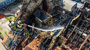 Zwei Feuerwehrleute spritzen am Sonntagmittag Wasser in die Brandruine zwischen Gerberstraße und Goldgrubengasse.