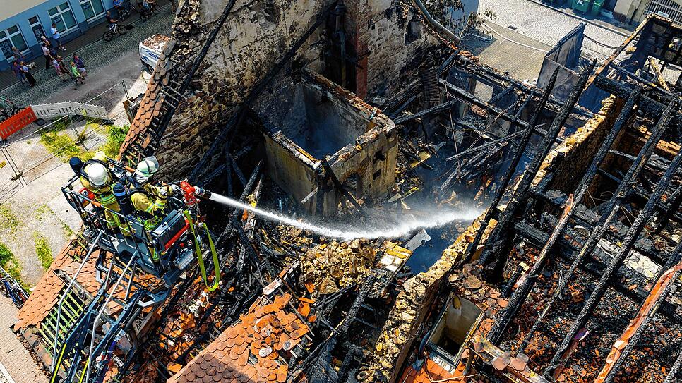 Zwei Feuerwehrleute spritzen am Sonntagmittag Wasser in die Brandruine zwischen Gerberstraße und Goldgrubengasse.