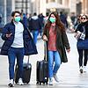 Touristen tragen in Mailand Mundschutz und rollen ihre Gepäck. Angesichts der raschen Ausbreitung des neuen Coronavirus in Italien macht ...