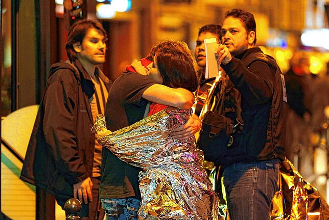 Überlebende des Attentats umarmen sich in der Nähe des Bataclan.