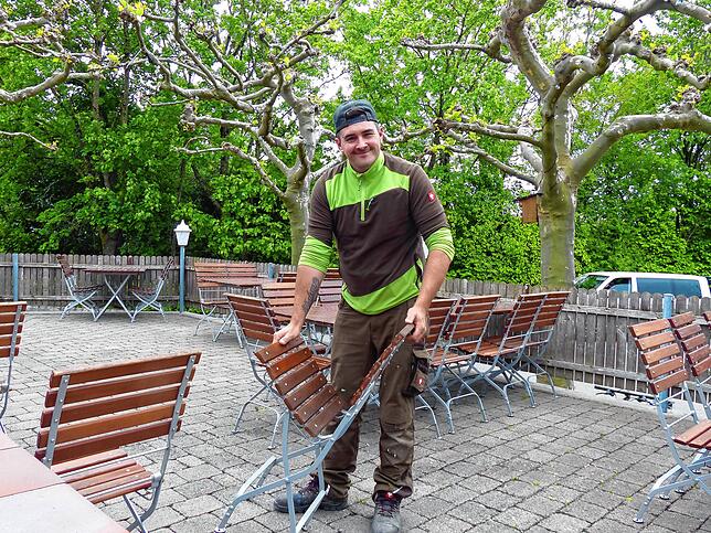 Sven Mohr, Abteilungsleiter Hausmeisterei, hofft auf besseres Wetter, während er die Stühle für die Gastronomie im Freien aufstellt.