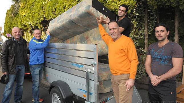 Joachim Mutschler und Ralf Holverscheid haben Adnan Al Merae, Aduan Al Merae und Nabhan Al Merae beim Aufladen einer Couch-Garnitur ...