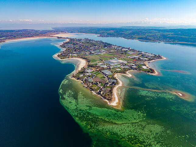 Die Reichenau aus der Luft betrachtet, links der Inseldamm, im Hintergrund Konstanz und die Alpen.