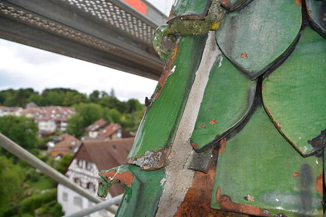 Auf dem Dachreiter sind teils noch über 500 Jahre alte gotische Biberziegel erhalten, so auch dieses mit Drachenkopf und -schwanz ...