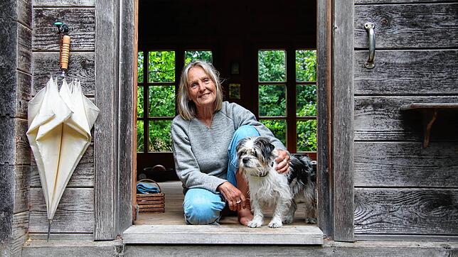 Anne Donath sitzt mit ihrem Hund im Eingang ihres Blockhauses in Steinhausen.