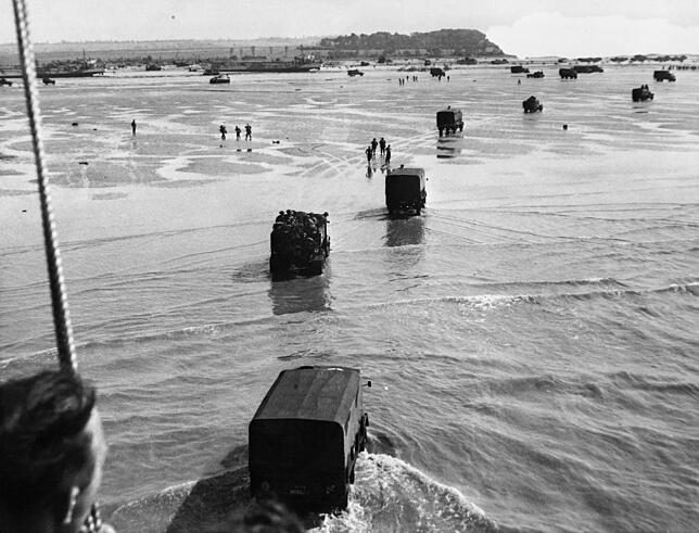 US-Lastwagen mit Nachschub fahren von Schiffen auf den Strand zu.