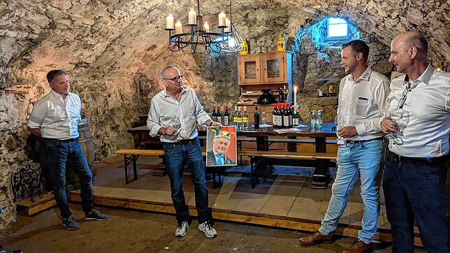Narrenrichter Jürgen Koterzyna hält ein Bild des früheren Beklagten Wolfgang Kubicki, der nicht selbst zur Weinübergabe kommen konnte.