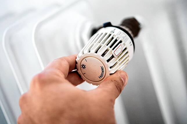 Ein Mann dreht in einer Wohnung am Thermostat einer Heizung. Die Menschen in Deutschland sollen wegen steigender Preise im laufenden ...