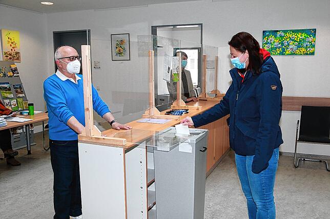 Im Foyer des Rathauses in Unterkirnach gibt eine Wählerin ihren Stimmzettel für die Landtagswahl am Sonntag ab. Die Wahlhelfer Bernhard ...